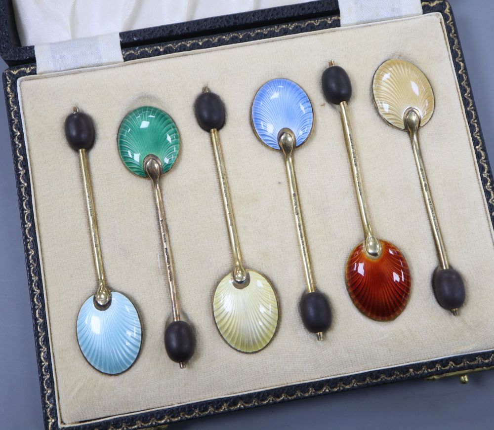 A cased set of six silver gilt and polychrome enamel bean end coffee spoons, William Suckling Ltd, Birmingham, 1955/6.